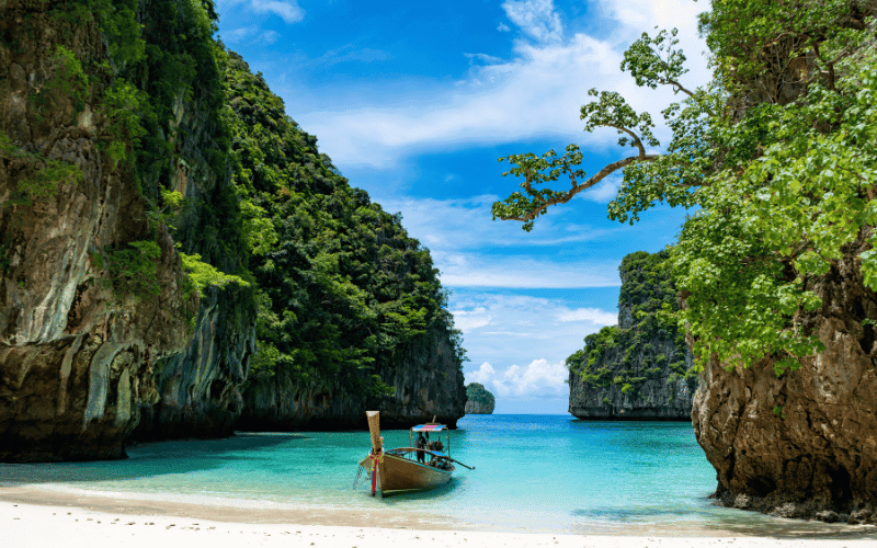 Long tail boat parked in one of the many coves of phi phi island and the blue waters in the background.