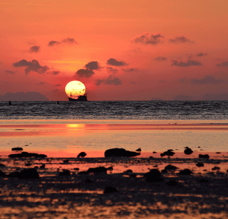 Phuket sunrise golden rocky beach reflection.